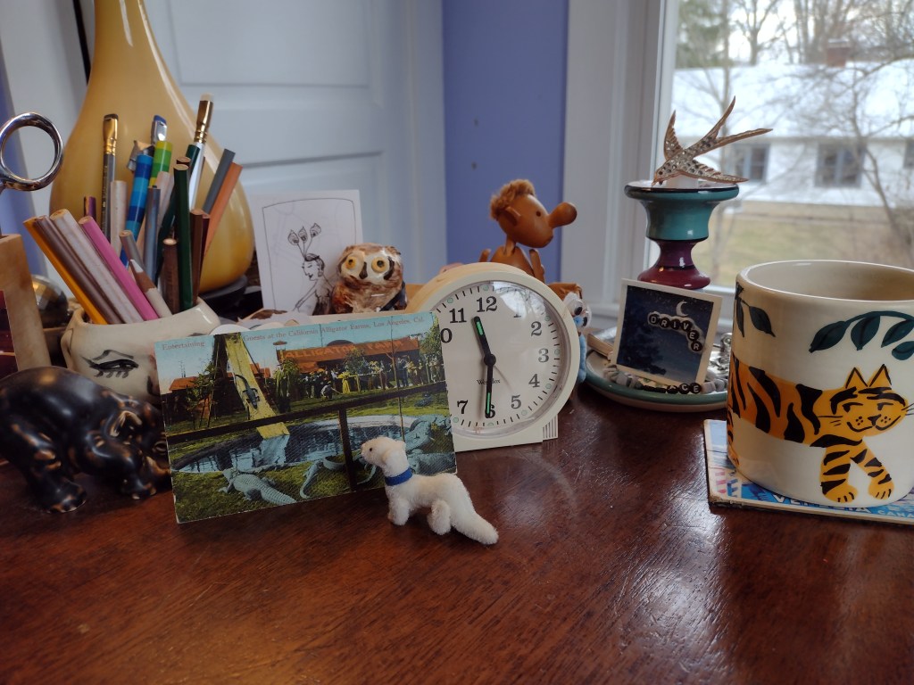assemblage of small items on desk, ermine, elephant, mug with tiger on it, Hans Bolling figure, clock, pencils, etc.